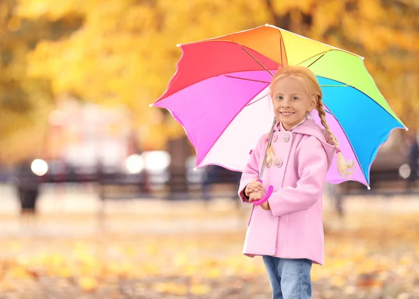 Menina bonito com guarda-chuva arco-íris no parque de outono — Fotografia de Stock