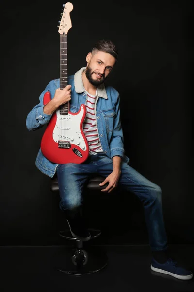 Jovem músico bonito com guitarra sobre fundo preto — Fotografia de Stock