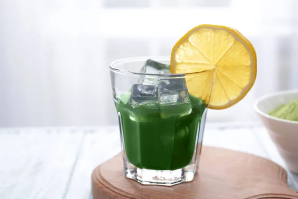 Glass of wheat grass juice with lemon on wooden table — Stock Photo, Image
