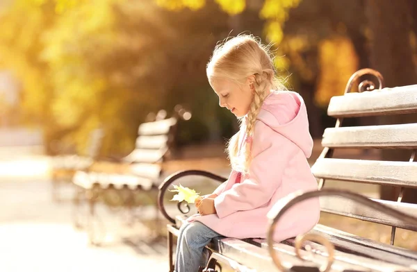 Ładna dziewczynka siedzi na ławce w parku jesień — Zdjęcie stockowe