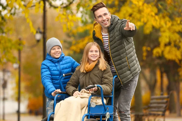 Adolescente en fauteuil roulant avec sa famille à l'extérieur le jour de l'automne — Photo