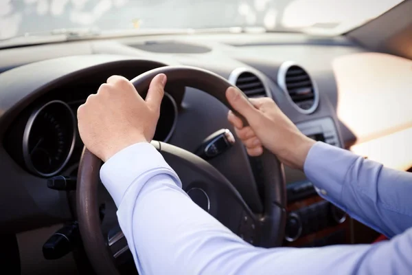 Young man holding hands on steering wheel of car — Stock Photo, Image