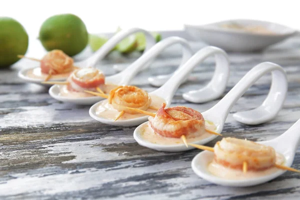 Ceramic spoons with bacon wrapped scallops and sauce — Stock Photo, Image