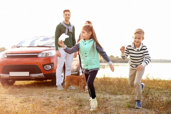 Милі діти грають і батьки біля машини, на відкритому повітрі — стокове фото
