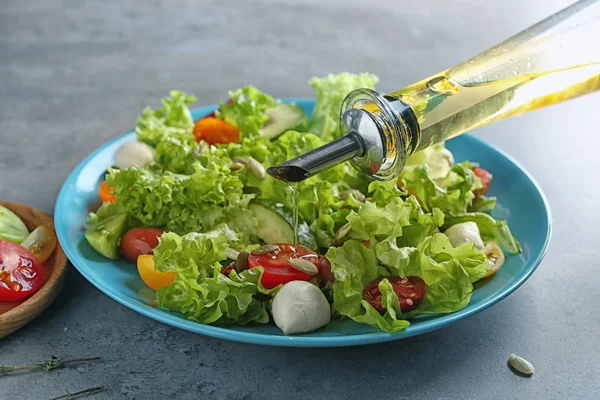 Öl zu leckerem Gemüsesalat auf Teller geben — Stockfoto
