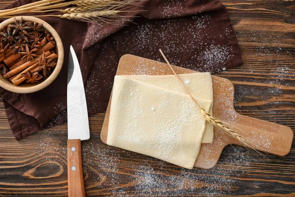 Wooden board with raw flaky dough — Stock Photo, Image