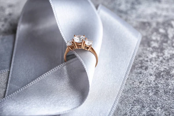 Fita com belo anel de noivado na mesa — Fotografia de Stock