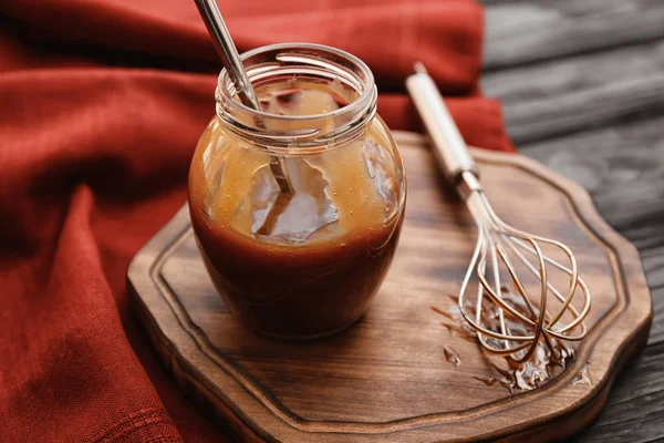 Jar fából készült táblán ízletes karamell öntettel — Stock Fotó