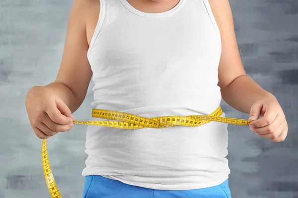 Ragazzo sovrappeso che misura la vita su sfondo grigio, primo piano — Foto Stock