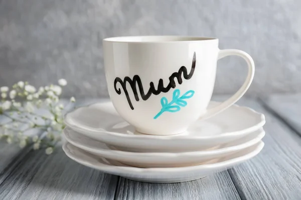 Cup with word MUM and saucers for Mother\'s day on table