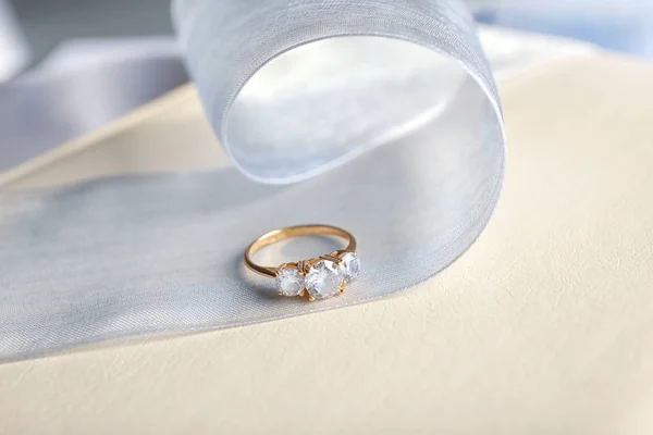 Hermoso anillo de compromiso y cinta en la mesa — Foto de Stock