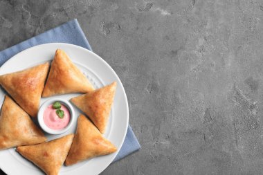 Plaka lezzetli samosas ve gri arka plan üzerine sos ile