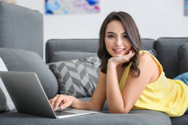  kadın kanepede yatan dizüstü bilgisayar ile