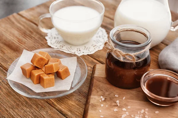 Komposisi dengan permen lezat dan saus karamel di atas meja — Stok Foto