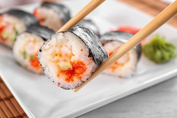 Pałeczki z smaczny sushi roll, zbliżenie — Zdjęcie stockowe