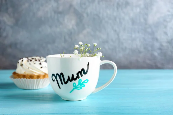 Cup with word MUM and dessert for Mother's day on table