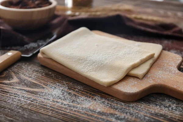 Wooden board with raw flaky dough — Stock Photo, Image