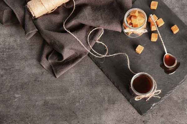 Composition with tasty candies and caramel sauce on table — Stock Photo, Image