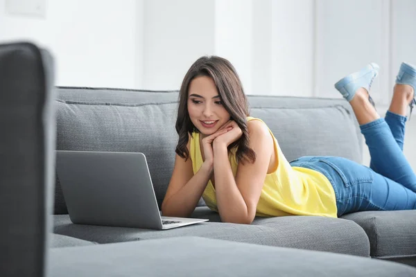 Женщина с ноутбуком лежит на диване — стоковое фото