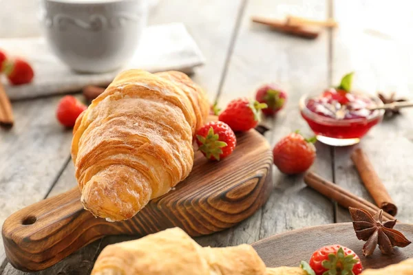 Tablero de madera con sabroso croissant en la mesa — Foto de Stock