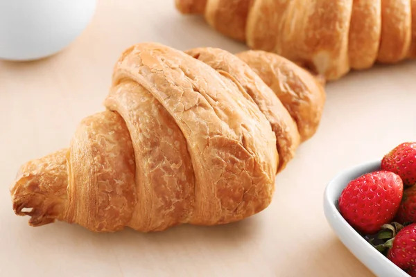 Croissant saboroso na mesa de madeira, close-up — Fotografia de Stock