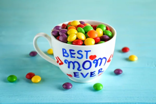 Cup with text BEST MOM EVER and candies  for Mother\'s day on table