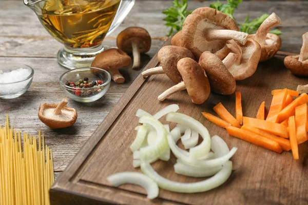 Bord met rauwe shiitake champignons en groenten op tafel — Stockfoto