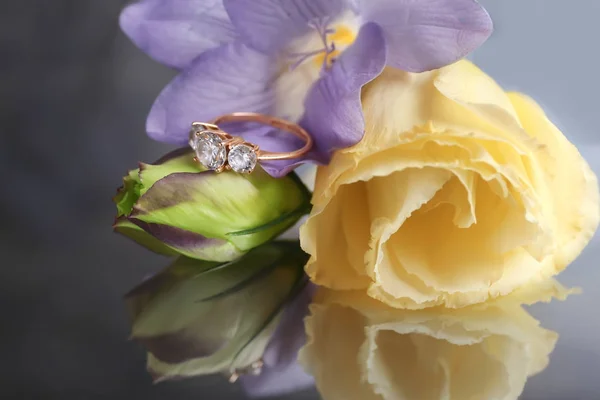 Flores con hermoso anillo de compromiso en superficie reflectante — Foto de Stock