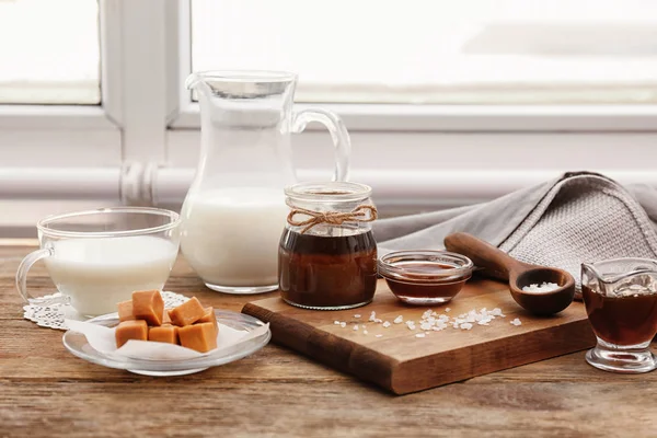 Komposisi dengan permen lezat dan saus karamel di atas meja — Stok Foto