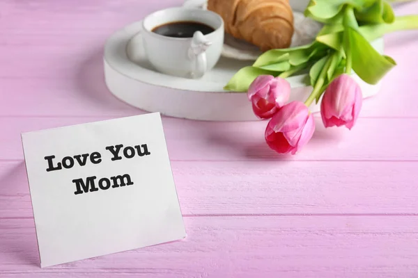 Poznámka: se slovy "Láska tě máma" a růžové tulipány na dřevěný stůl — Stock fotografie