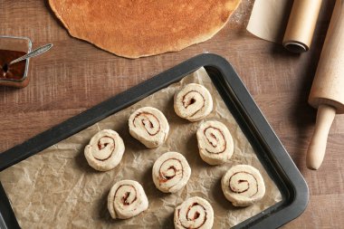 Tablo üzerinde ham tarçınlı çörek ile fırın tepsisine