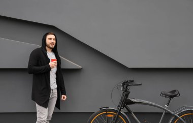 Yakışıklı genç hipster adam yakınındaki duvara açık havada bisiklet ile
