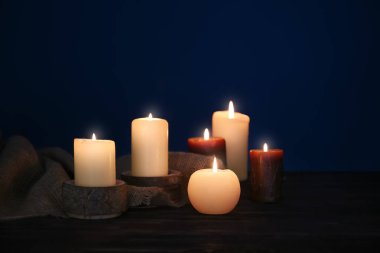 Koyu arka plan karşı masada yanan mumlar