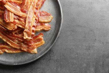Plate with cooked bacon rashers on table clipart