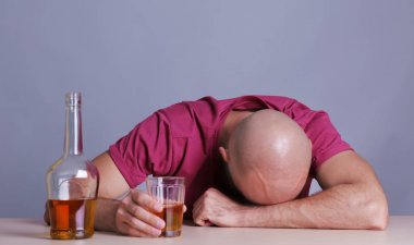 Viski ile masada oturan sarhoş adam. Alkolizm kavramı