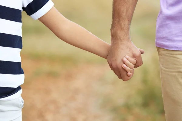 Niño pequeño sosteniendo la mano de su padre al aire libre, concéntrese en las manos — Foto de Stock