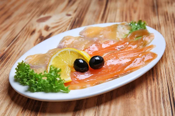 Piatto con gustoso carpaccio di pesce sul tavolo di legno — Foto Stock