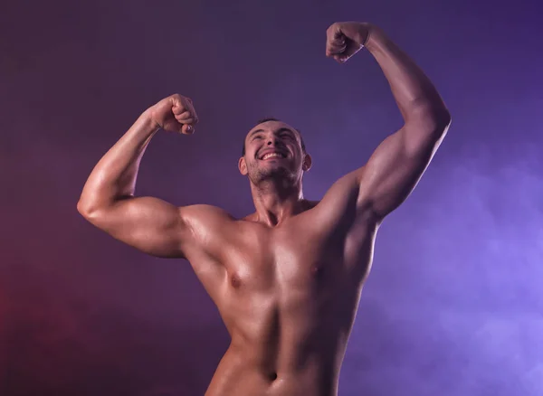 Muscoloso giovane bodybuilder in fumo colorato — Foto Stock