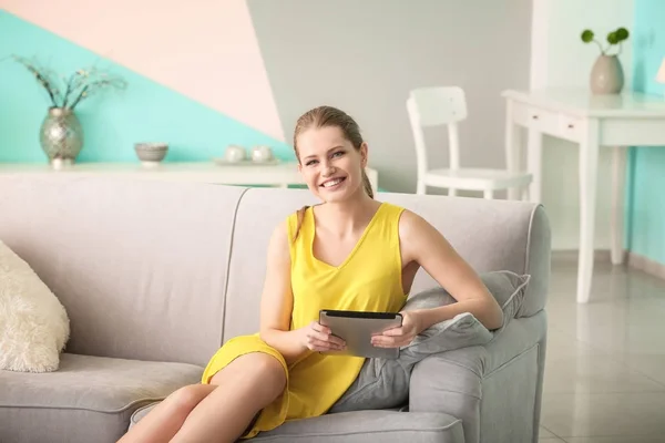 Vacker kvinna med TabletPC vila på soffan hemma — Stockfoto