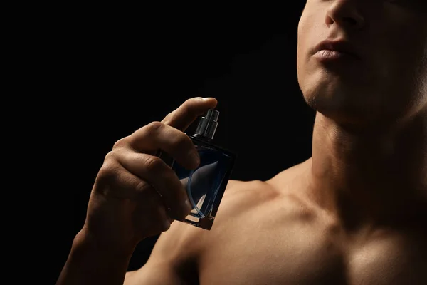 Bel homme avec bouteille de parfum sur fond sombre, gros plan — Photo