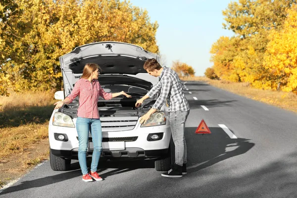 Jong koppel ruzie in de buurt van gebroken auto buiten — Stockfoto