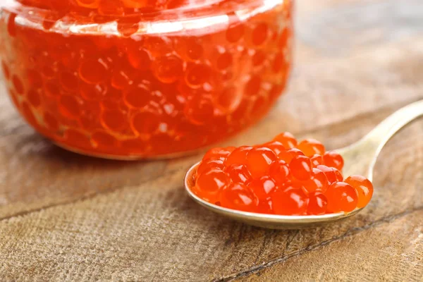 Frasco e colher com delicioso caviar vermelho na mesa, close-up — Fotografia de Stock