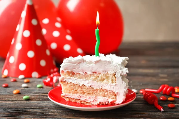 Pedaço de bolo de aniversário com vela na mesa — Fotografia de Stock