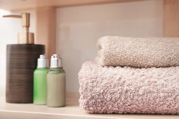 Čisté ručníky a kosmetiky na poličce v koupelně — Stock fotografie