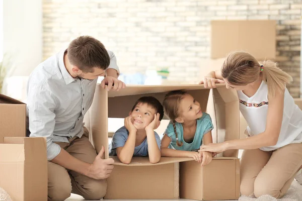 Os pais brincam com as crianças enquanto desempacotam coisas em um novo apartamento — Fotografia de Stock