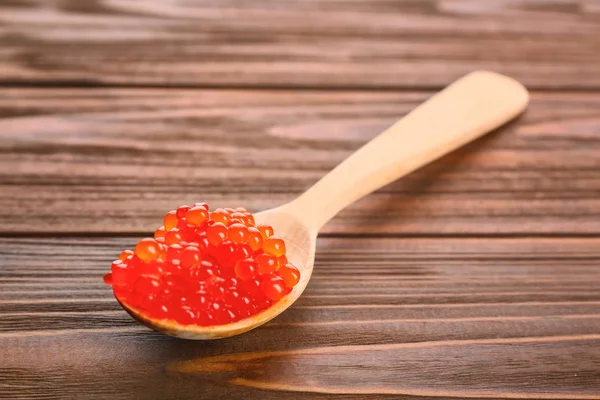 Cuchara con delicioso caviar rojo sobre fondo de madera —  Fotos de Stock
