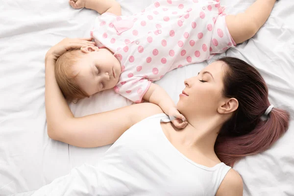 Ibu muda dan bayi lucu tidur di tempat tidur — Stok Foto