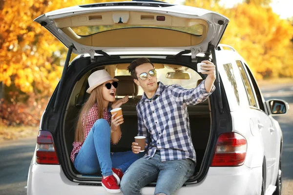 Belle jeune couple prenant selfie dans le coffre de la voiture — Photo