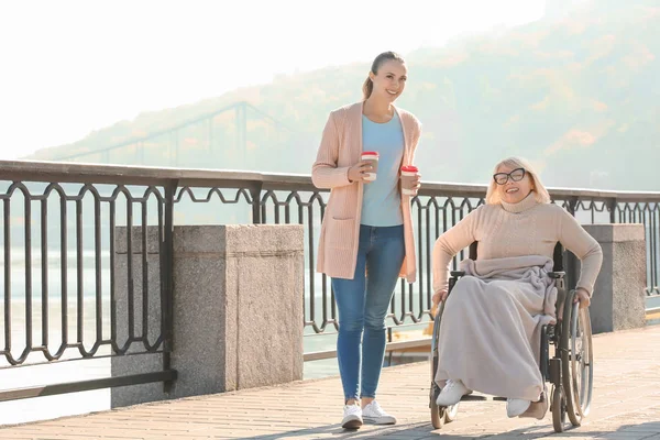 Mujer mayor discapacitada y cuidadora joven al aire libre — Foto de Stock
