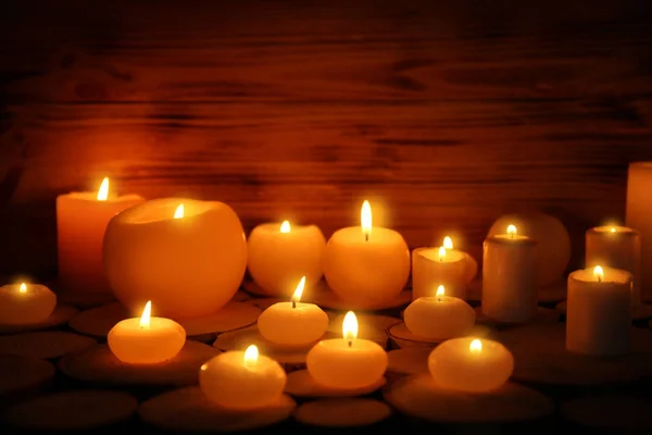 Muitas velas em chamas no fundo de madeira — Fotografia de Stock